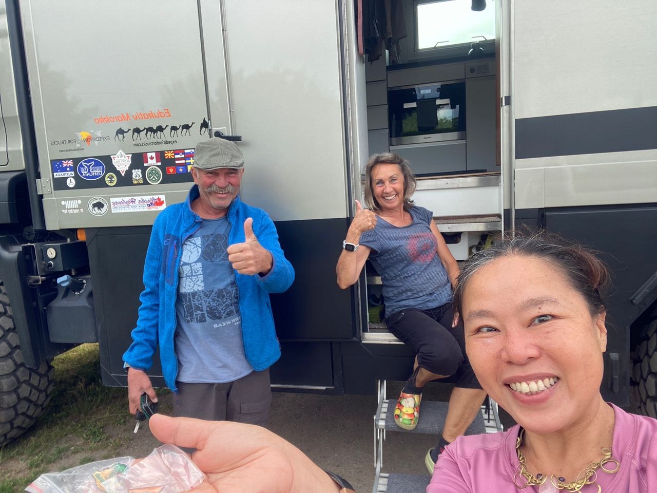 Tuzi with a German overland couple beside their expedition camper in Kaunas